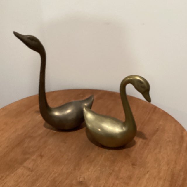 This product is a pair of vintage solid brass swan figurines with a mid-century modern sculptural design. The figurines...