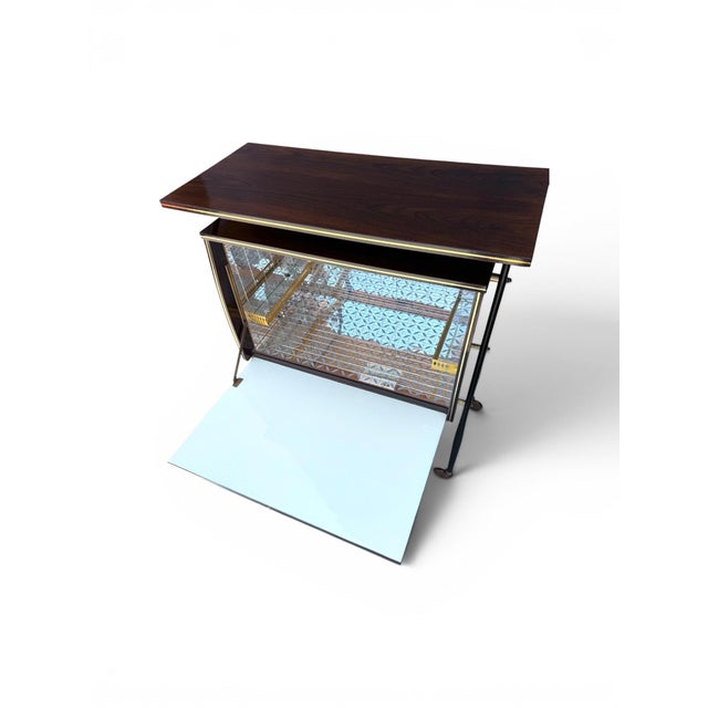A stylish 1950s Italian portable bar cabinet on wheels, featuring a richly inlaid wood and veneer exterior with a...