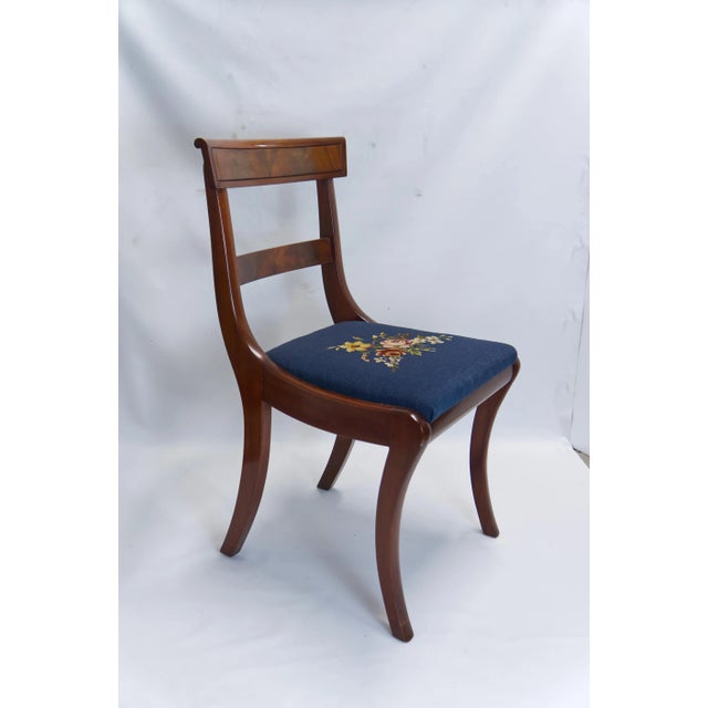 A set of 4 late Victorian mahogany dining chairs featuring floral needlepoint navy blue seats. One captain chair with arm...