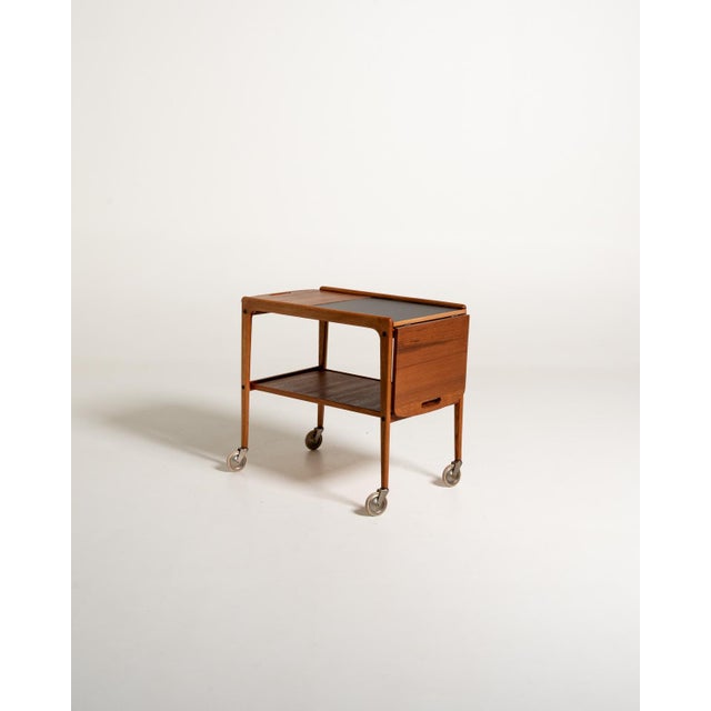 "Thea" serving trolley designed by Yngve Ekström, 1960s, in oak and teak, with a black laminate central shelf and drop-...