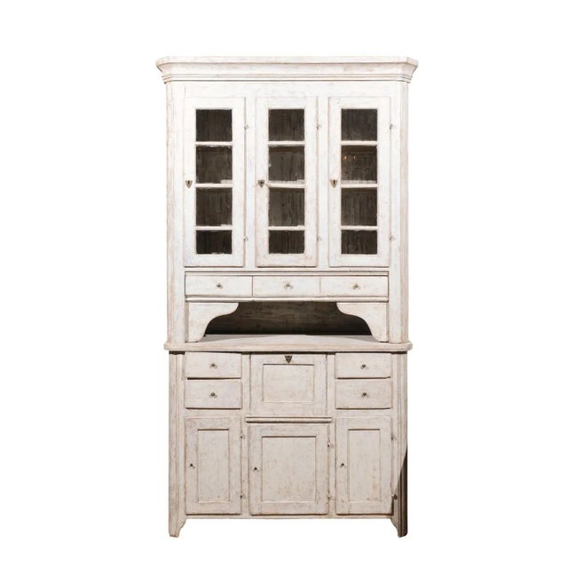 A Swedish two-part painted wood vitrine cabinet from the early 19th century with glass doors, drawers and distressed...