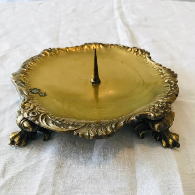 Very unique, ornate brass candleholder with a floral border and paw feet. Surface area ( for candle) is about 5” in diameter.