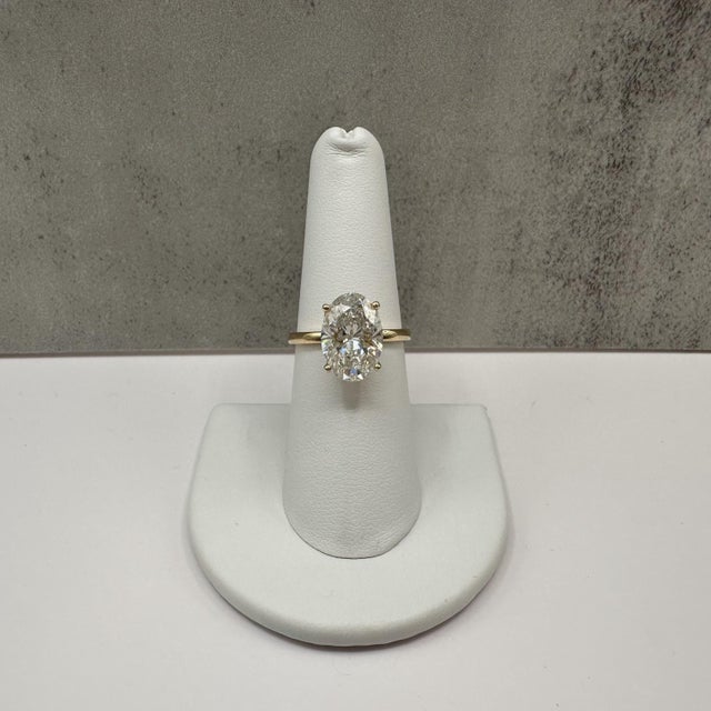 This stunning oval cut lab grown diamond engagement ring is crafted in 14K yellow gold and showcases an impressive 4.03...