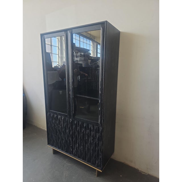 This Luxe Showcase entertainment center features a sleek black finish with textured wood detailing on the lower panels and...