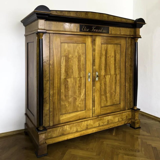 Large two-door wardrobe in ash and cherry with fillet band inlays and ebonised columns. The cornice with accentuated...