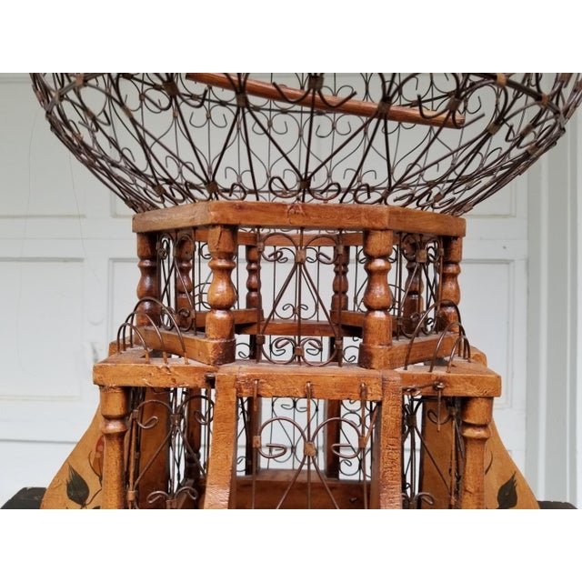 A 20th Century Victorian style wood and wrought iron “Balloon" form bird cage with mahogany stained wood and wrought iron...