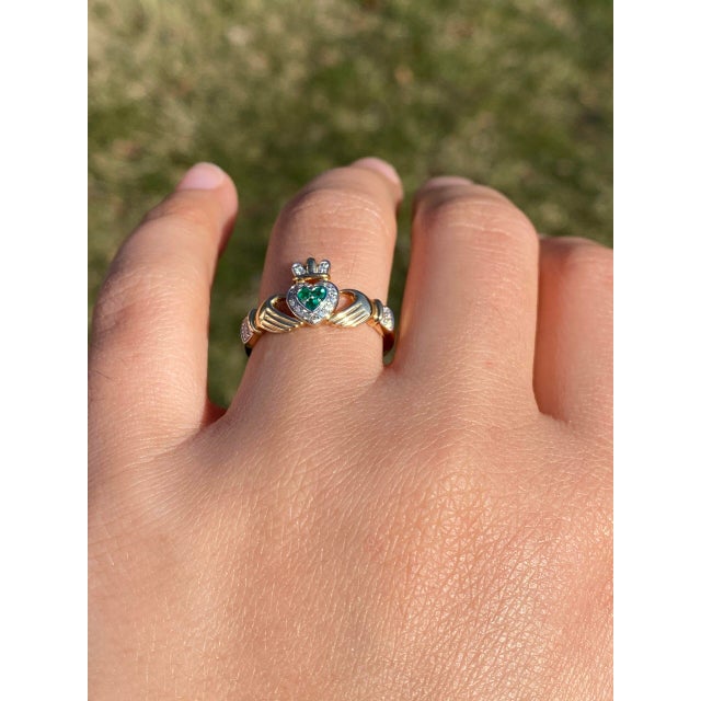 The Ennis: Designer Signed Natural Emerald and Diamond Claddagh Ring. This exquisite ring features a striking centerpiece...