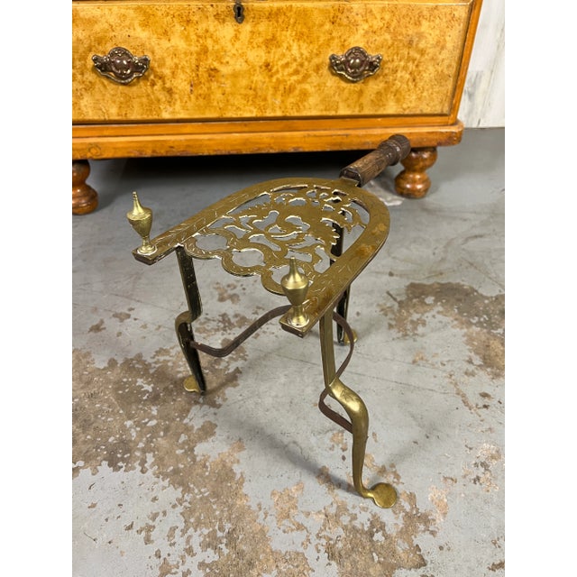 Handcut pierced brass trivet with turned wood handle and wrought iron base.