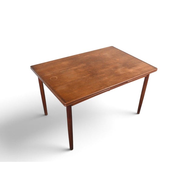 This draw-leaf dining table was crafted in Denmark during the 1960s. The solid teak top extends via a draw-leaf mechanism...