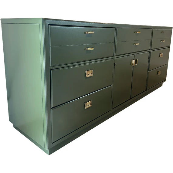 A long, modern sideboard in a deep blue-green finish with a streamlined, symmetrical layout. It features multiple drawers...