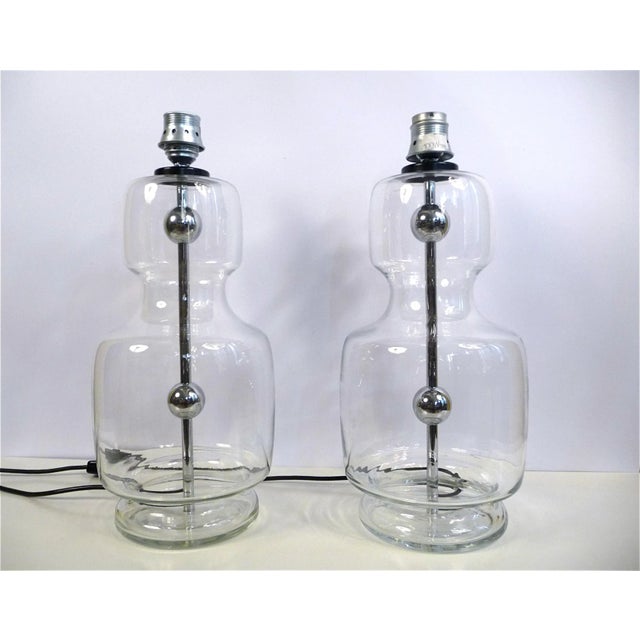 This set of two large table lights was made in Germany during the 1960s. The lamps feature vase-shaped bases of clear...