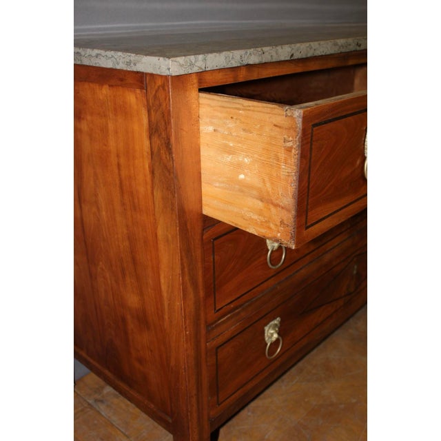 A Directoire period walnut commode, decorated with a diamond pattern of dark wood marquetry, featuring three drawers,...