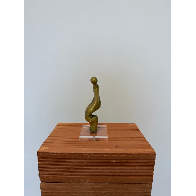 Brazilian modern abstract figurative sculpture of a person sitting rendered in bronze and attached to an acrylic base....