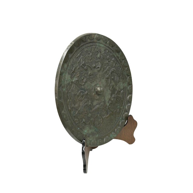 Discover a rare masterpiece of ancient artistry with this exquisitely crafted bronze mirror. Its surface, rich with the...