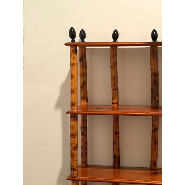 Sensational very tall elongated bamboo and wood etagere bookcase having a warm tortoise patina and black iron finials and...