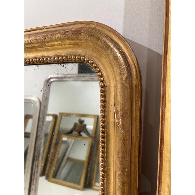 A grand 19th century French Louis Philippe mirror featuring a richly gilded frame with softly rounded corners and a...