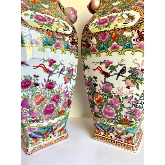 Here is a striking pair of hand-painted Chinese porcelain vases featuring elaborate Famille Rose–style decoration and rare...