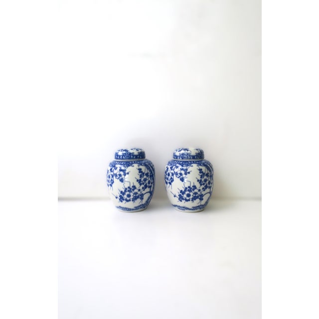 A pair of blue and white porcelain ginger jars with cherry blossom design, in the style of Imari Porcelain, circa mid-20th...