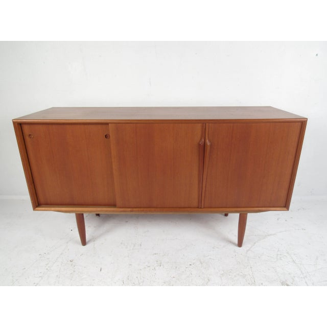 Impressive mid-century modern credenza with sculpted pulls, tapered legs, and drawers with dovetailed joints. The elegant...