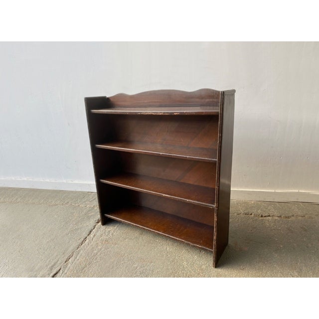 A free-standing open fronted vintage bookcase with 4 shelves. The two end supports taper towards the top. Made from dark...
