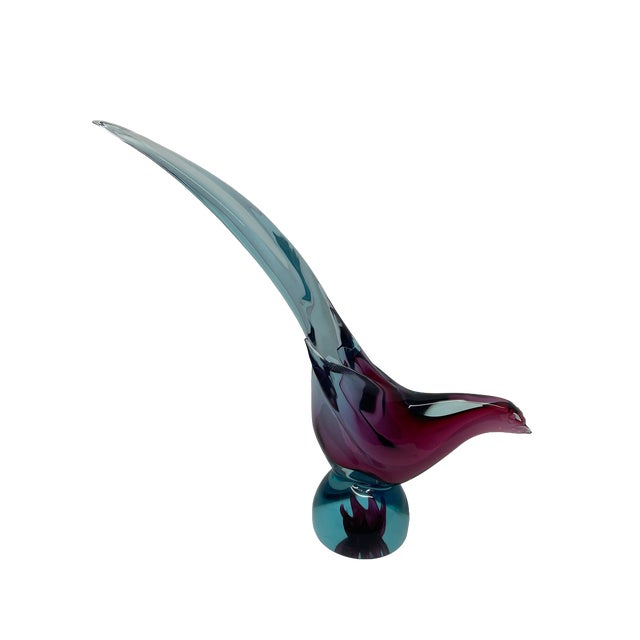 A Murano glass bird sculpture with a dramatically elongated tail sweeping upward from a rounded body. Blue and turquoise...
