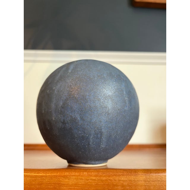 Sculptural globular stoneware vessel with a finely balanced orb form and a softly textured matte glaze in tonal charcoal...