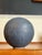 Sculptural globular stoneware vessel with a finely balanced orb form and a softly textured matte glaze in tonal charcoal...