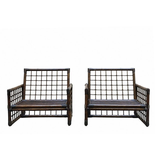 Pair of armchairs from the basilan i series. rattan, brass, leather straps. manufactured by compagnia delle filippi, a...