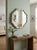 Sculptural round wall mirror featuring a dimensional faux-bois frame modeled as an overlapping arrangement of naturalistic...