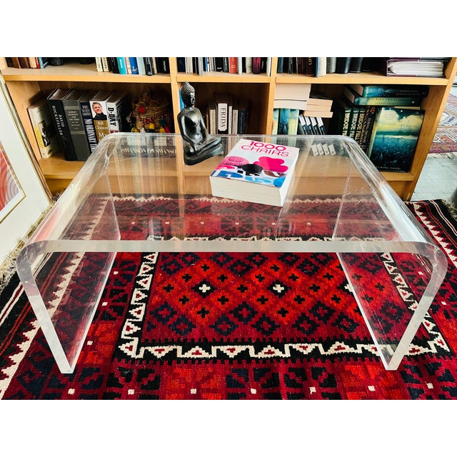 This thick lucite waterfall coffee table has plenty of mod style, adding a lot of surface storage with understated ease....
