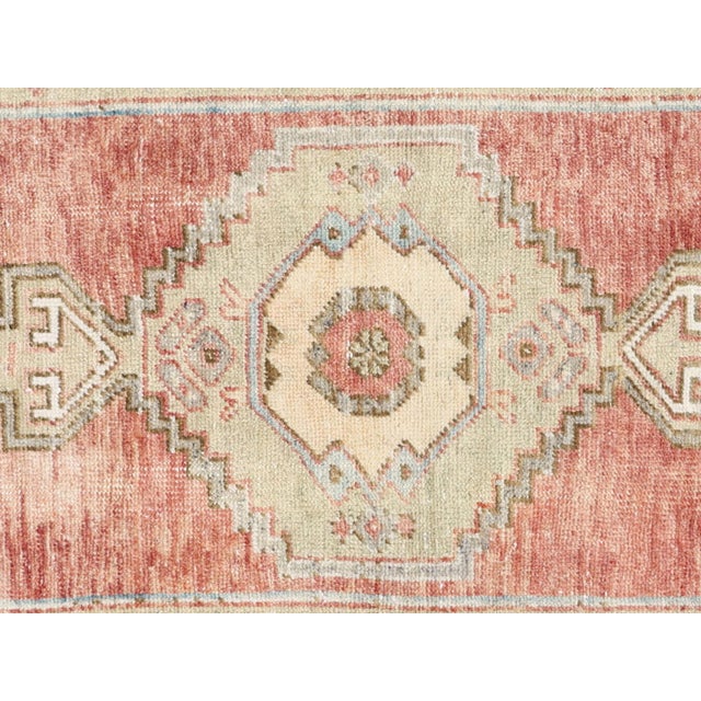 Expertly crafted in Turkey, this vintage Oushak rug measures 2'9" x 5' and adds a touch of timeless elegance to any space....