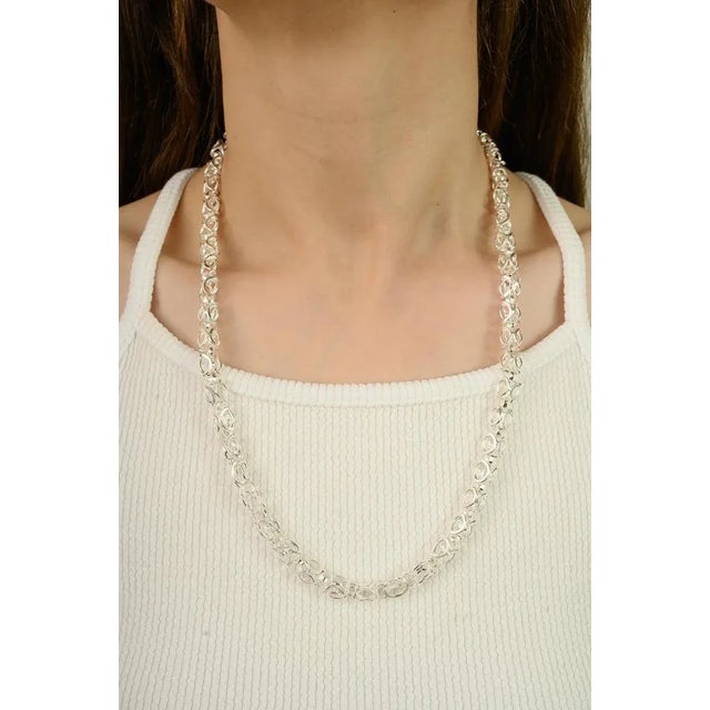 A striking link chain necklace crafted from pure 925 sterling silver, designed with an intricate interwoven pattern that...