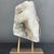 A striking white quartz crystal specimen displayed on a custom metal stand, showcasing the natural beauty and...
