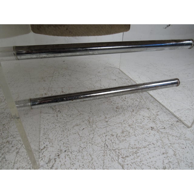 An unusual pair of vintage modern lounge chairs that feature Lucite sides connected by chrome cylindrical stretchers. The...