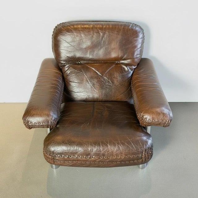Leather armchair with thick brown leather cushions and tubular chrome frame and feet, similar to models by De Sede and...