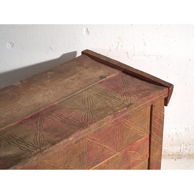 This antique carved chest in pine wood is a Central European peasant chest with incised carving and traces of red...