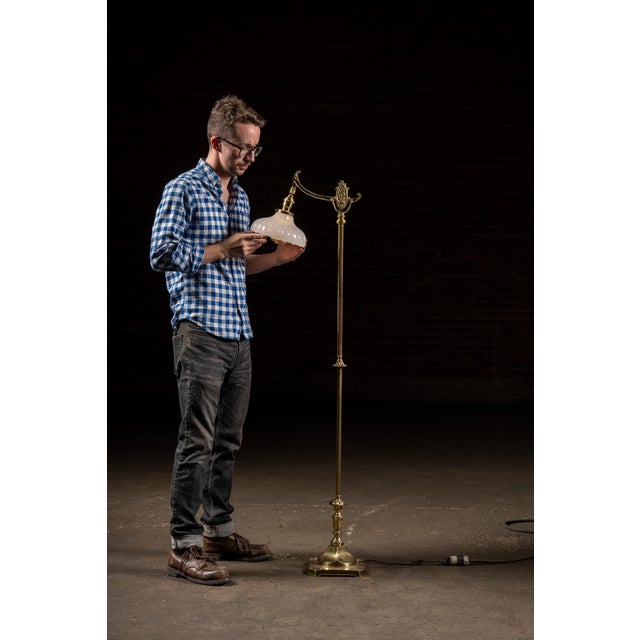 Cast brass bridge arm floor lamp with scroll detailing and weighted square base. A striking example of early 20th-century...