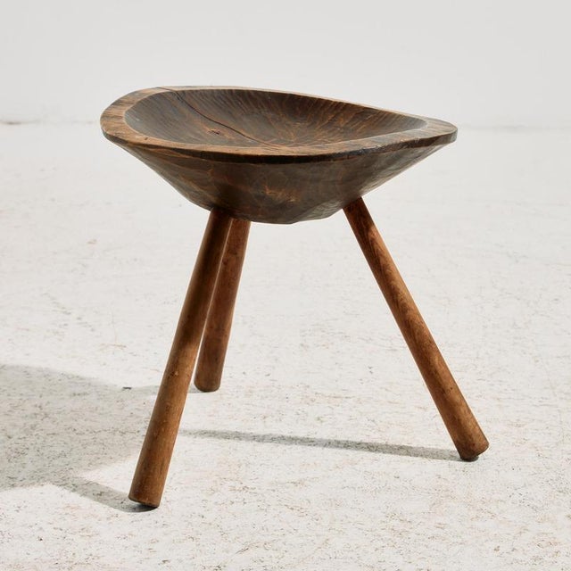 Handcrafted milking stool with three legs. The surfaces have some scratches and wear in places.