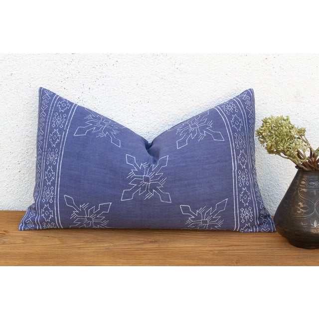 A four-petal flower-star medallion, hand block-printed in white, repeats across a deep indigo linen ground on this lumbar...