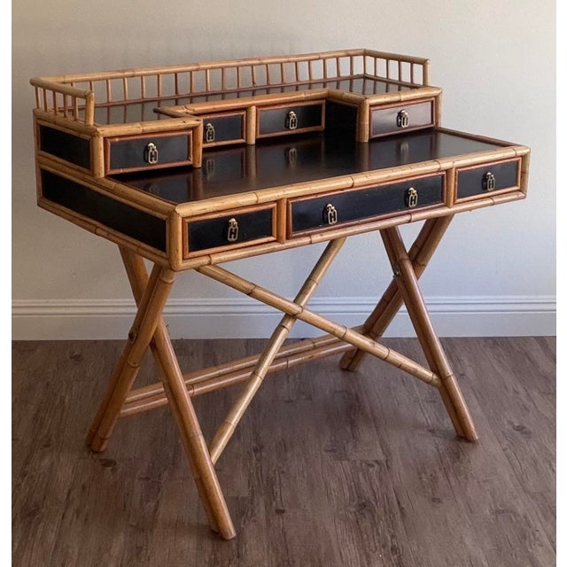 Attributed to E. Murio, this vintage Campaign-style faux bamboo writing desk showcases timeless Hollywood Regency and...