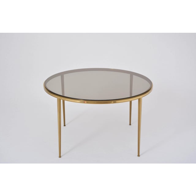 This is a circular coffee table produced by Vereinigte Werkstätten, München, in the 1960s. The top is made of smoked...
