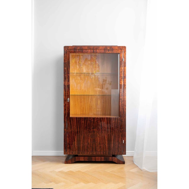 This Art Deco display cabinet dates from the 1930s and originates from France. The cabinet features a wooden structure...