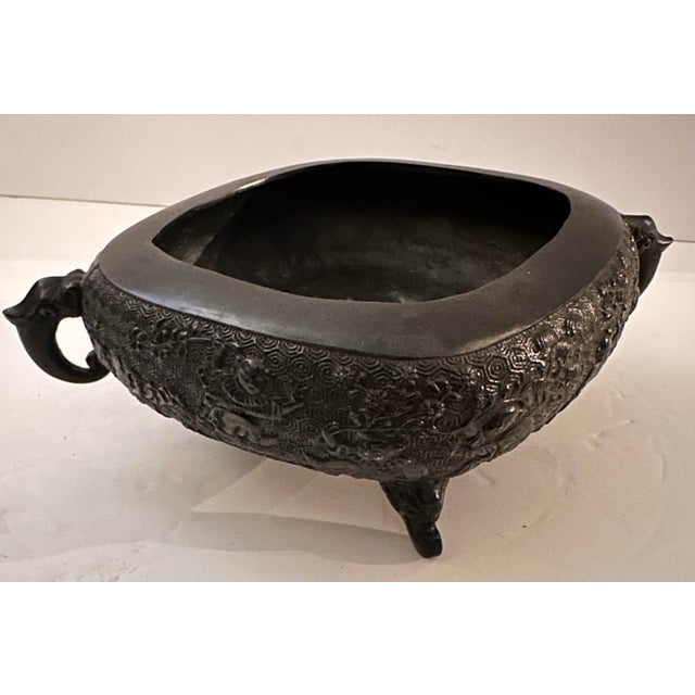 A small, deep-bellied bronze or vessel with a dense, all-over textured pattern of interlocking spirals and medallions,...