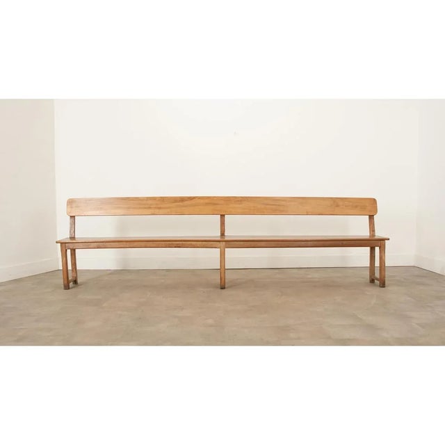 A very long French armless pine bench from the turn of the 20th century. The hardwood is very smooth with a fine patina....