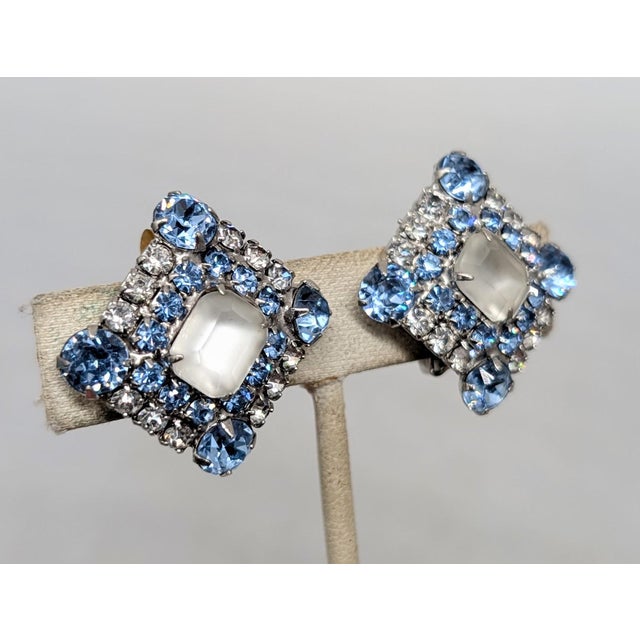1960s rhodium plated square prong set frosted emerald cut rhinestone center with small round faux-aquamarine surround and...
