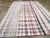 This Mid-20th century Turkish Flatweave Kilim rug, features a vibrant plaid-inspired design woven in soft, naturally faded...