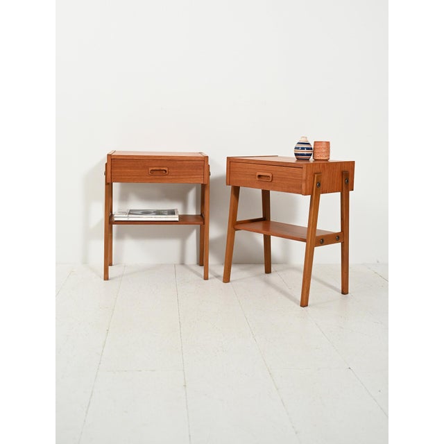 Pair of 1960s Scandinavian teak nightstands with a drawer, magazine rack, and exposed brass details. Pair of 1960s...