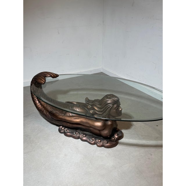 Unique sculptural coffee table featuring a striking mermaid base in bronze-look kunststof, combined with an elegant oval...