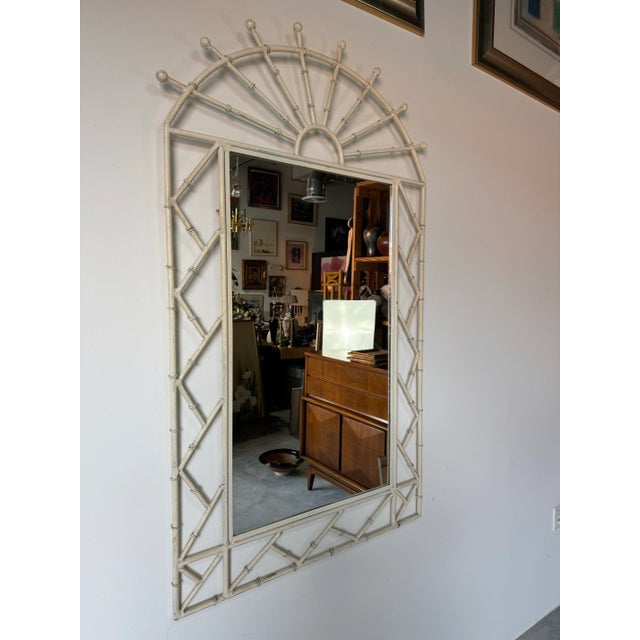 Elegant and timeless, this 1970’s Coastal Hollywood Regency wall mirror features a striking arched faux bamboo design...