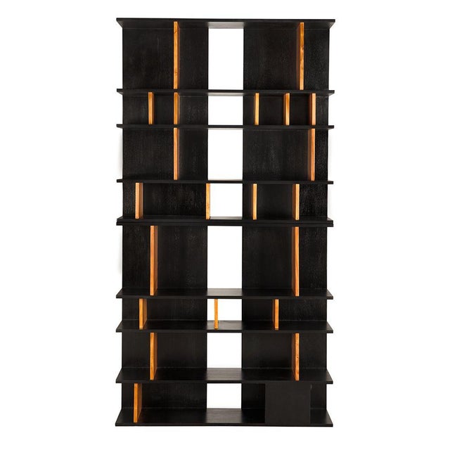 A sculptural shelving unit featuring alternating hand-rubbed black horizontal planes and warm teak vertical dividers,...